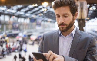 Man in a busy outdoor area using his smart phone
